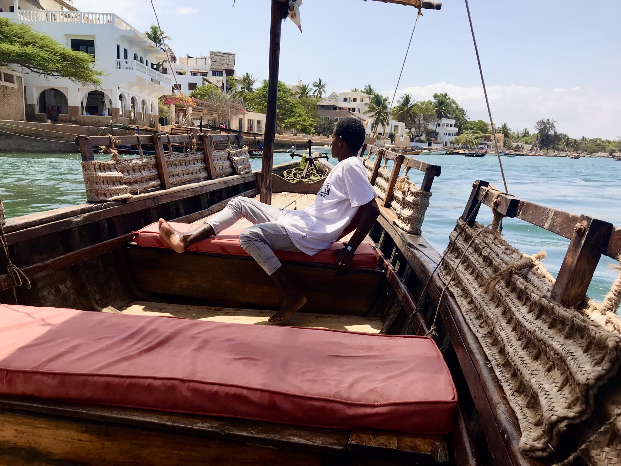 Man boarding a traditional dhow boat in Lamu, Kenya; a popular budget travel in Kenya destination